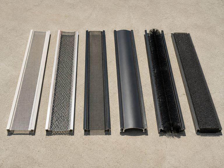 Six common gutter guard types shown in 3-foot sections laid side by side on a clean concrete driveway.