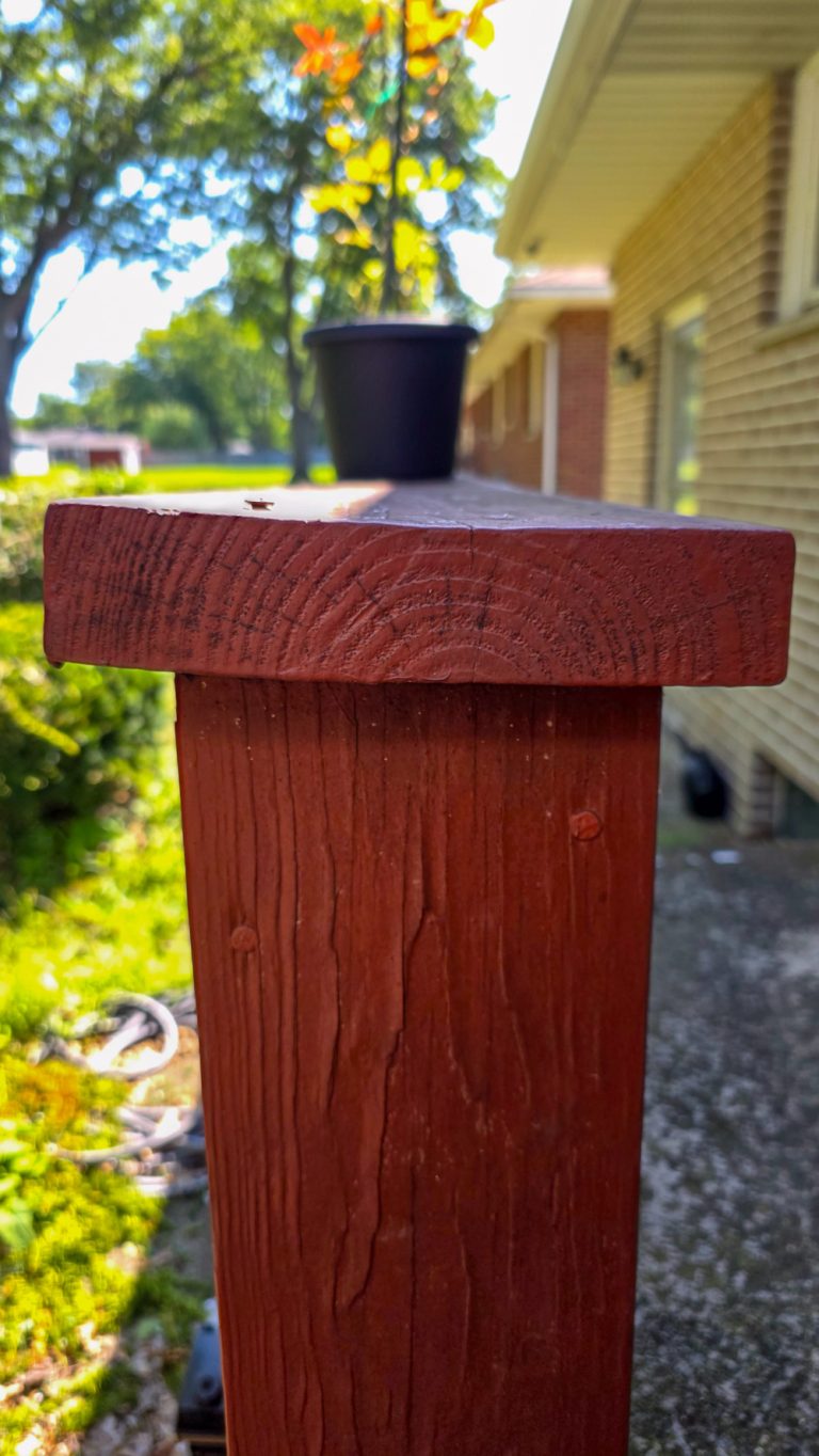 Low side-angle close view of redwood painted top railing board that has twisted