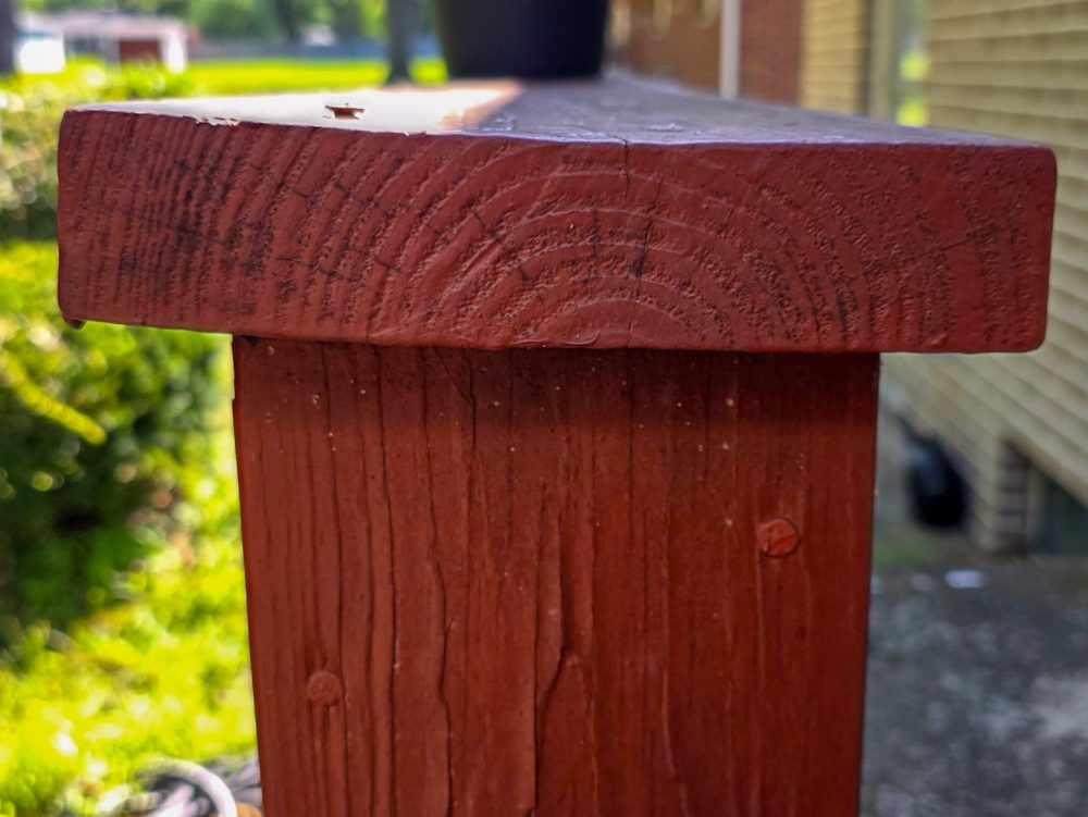 Low side-angle close view of redwood painted top railing board that has twisted